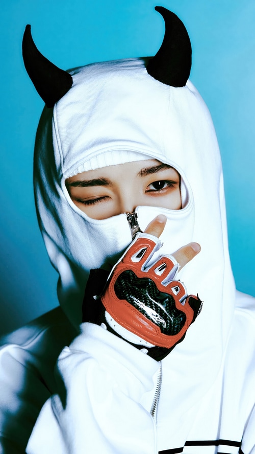 Renjun from NCT DREAM wearing a white hoodie with devil horns