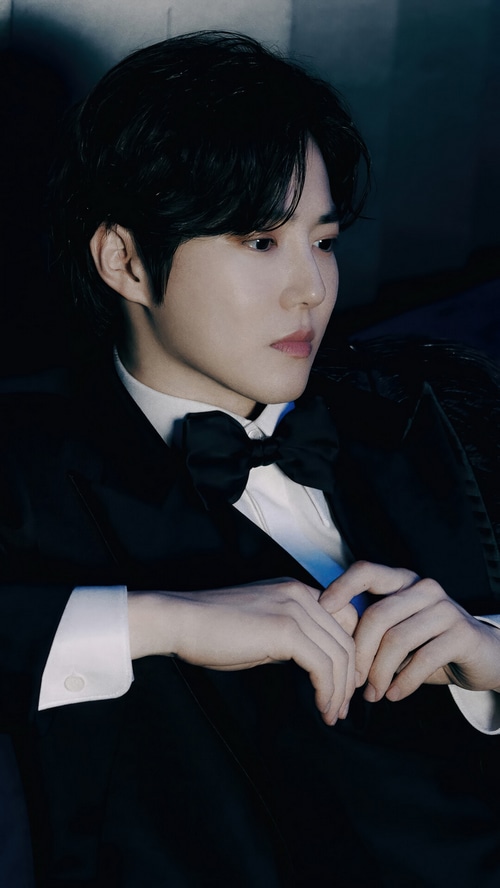 Suho in a black tuxedo with a bow tie