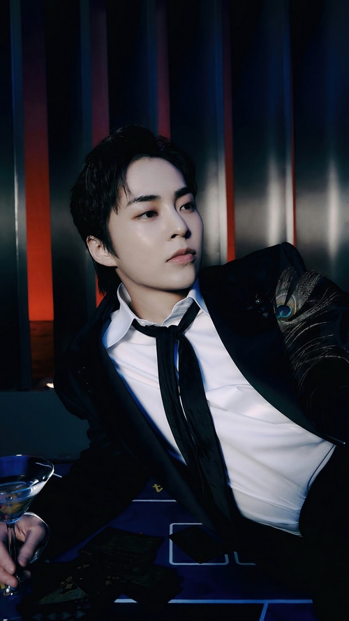 Xiumin in a black suit with a peacock feather detail