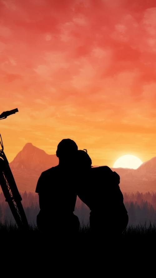 Couple silhouetted against a vibrant sunset with mountains