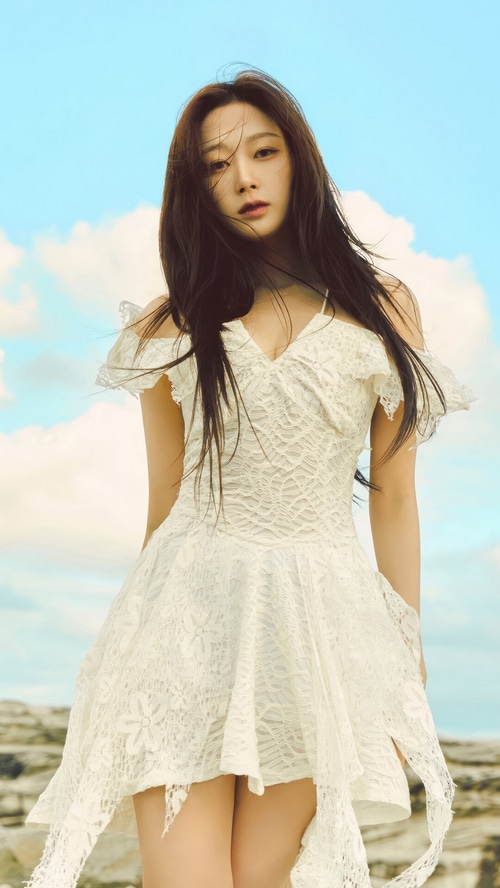 Giselle in a white lace dress against a blue sky