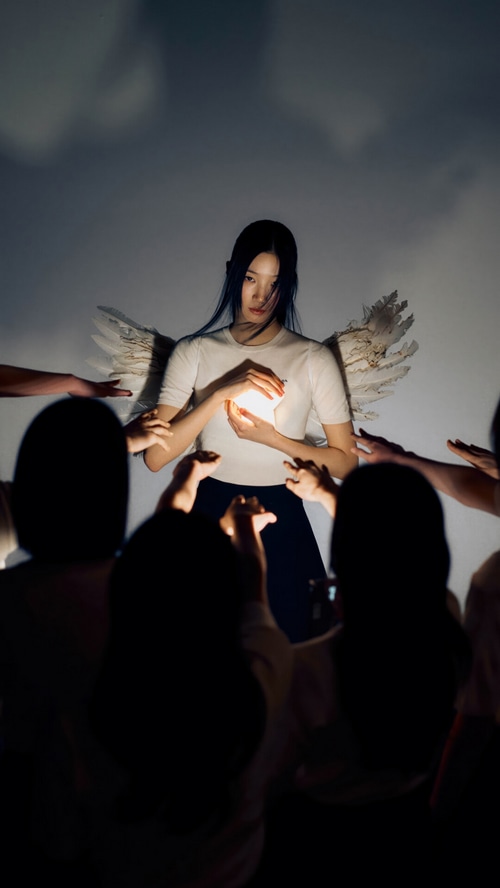Kazuha of LE SSERAFIM holds a glowing orb with angel wings