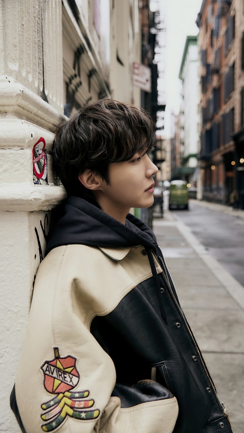 J-Hope leans against a pillar on a city street