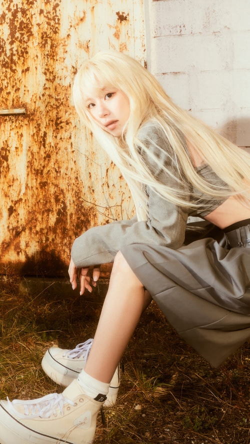 Chaeyoung from TWICE posing in front of a rusty wall
