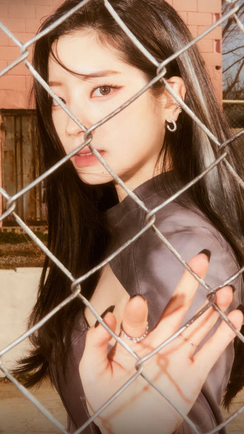 Dahyun from TWICE behind a chain-link fence