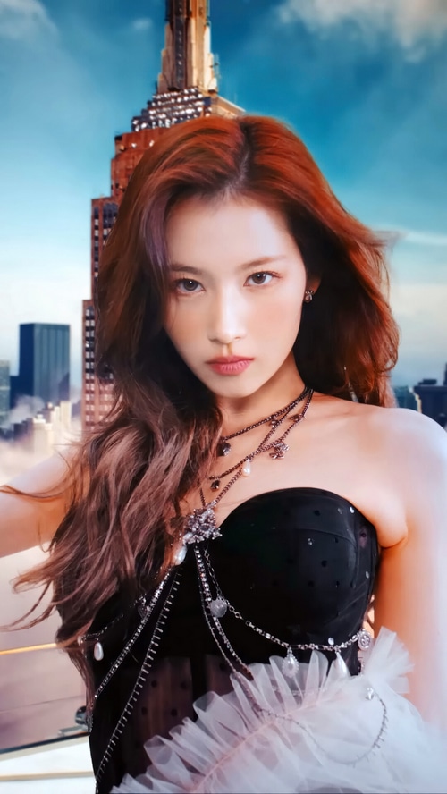 Sana from TWICE in a black dress with city background