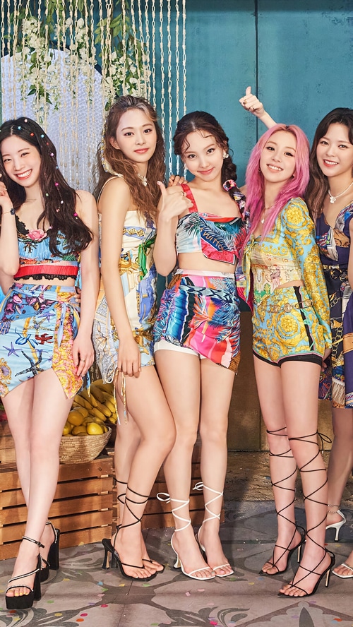 TWICE members posing in colorful outfits