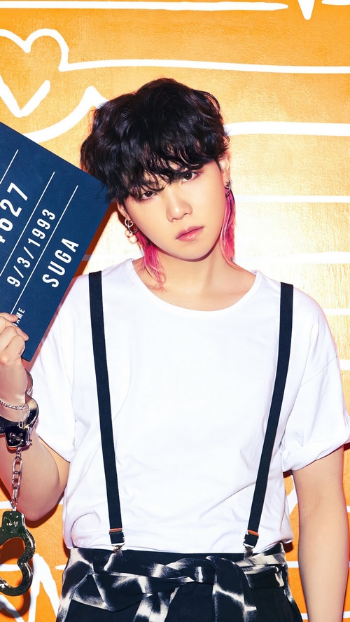 Suga of BTS holding a mugshot sign
