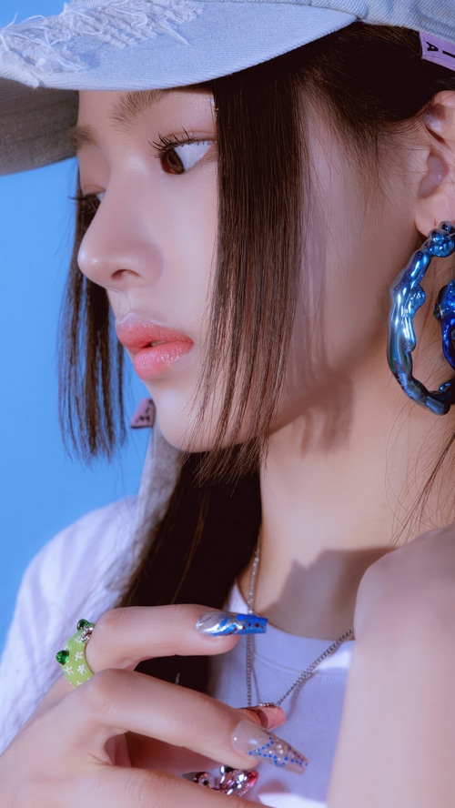Minji from NewJeans wearing a blue earring and frog ring