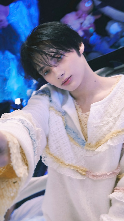 Huening Kai in a white ruffled outfit
