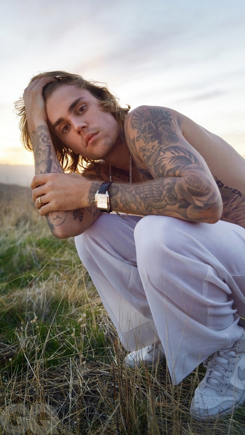 Justin Bieber posing in a field at sunset