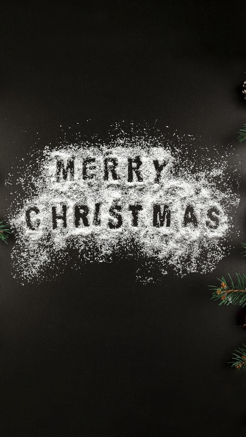 Merry Christmas written in snow with pine branches