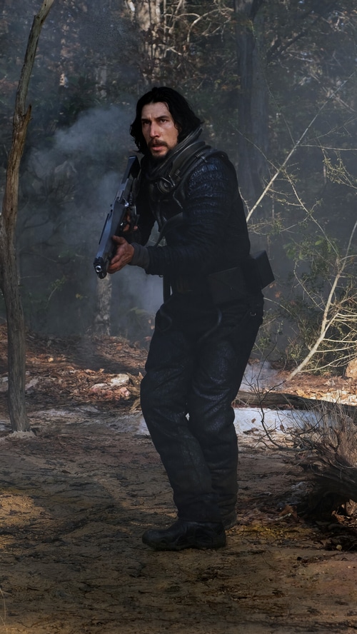 Adam Driver in a forest with a rifle