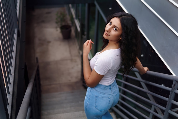 Model in white top and jeans on stairs