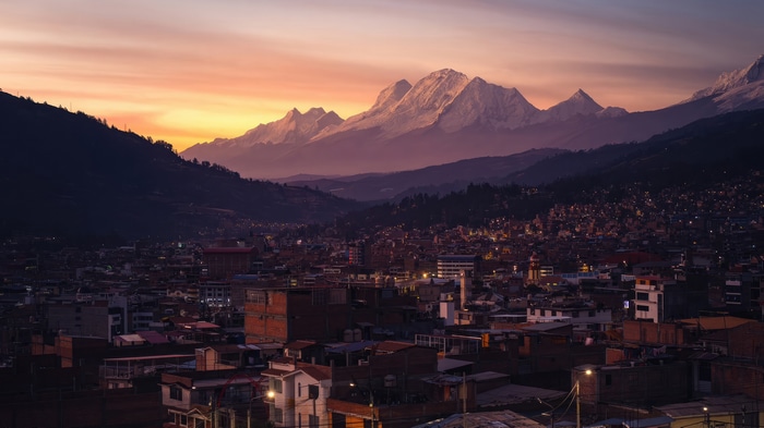 Cityscape at sunset with snow-capped mountains