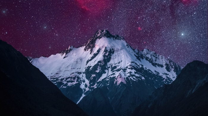Snow-capped mountains under a starry purple sky