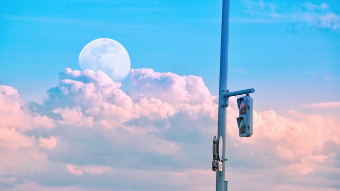 Traffic light against a cloudy sky with moon