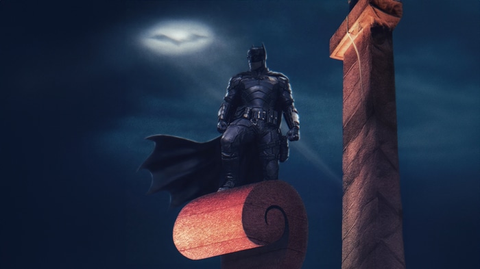 The Batman stands on a pillar under the moon