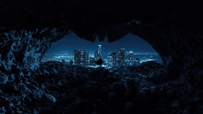 Batman overlooking a city from a cave