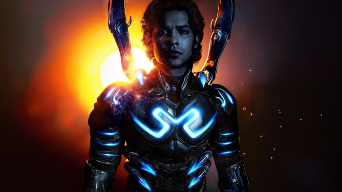 Blue Beetle in his suit with a bright sun behind him