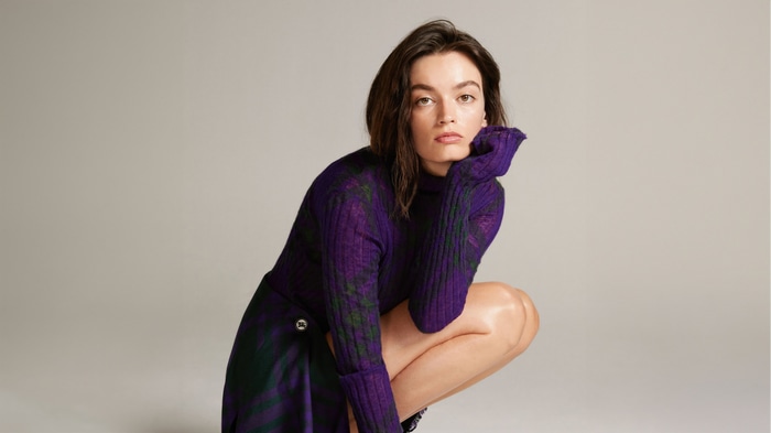 Emma Mackey in purple turtleneck and skirt