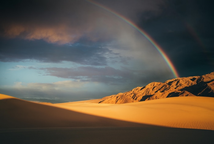 Rainbow over desert mountains and sand dunes