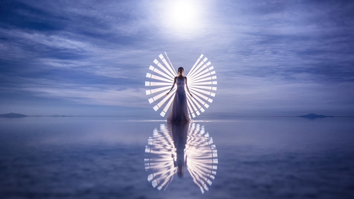 Woman with light wings reflection on water