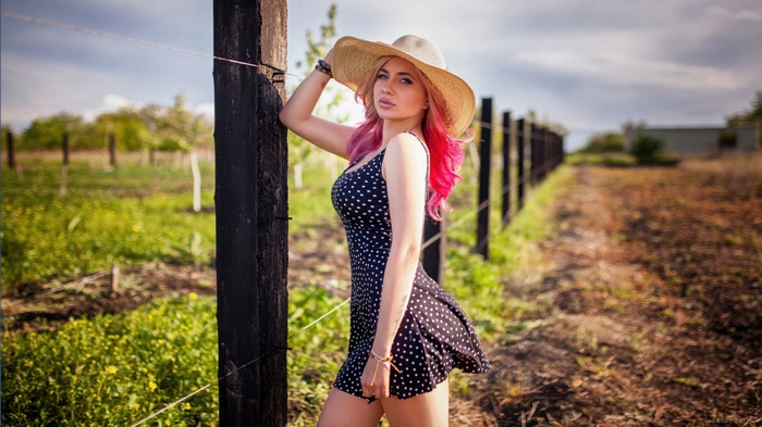 Woman with pink hair wearing a polka dot dress and hat
