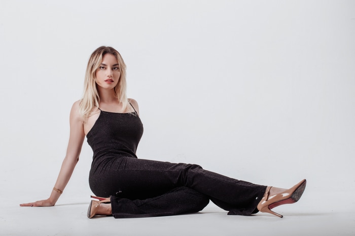 Model in black dress sitting on white background