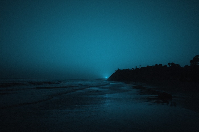 Ocean waves at dusk with a distant light on a hill