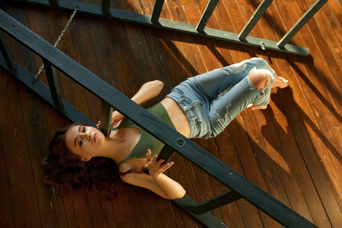 Model in ripped jeans lying on wooden floor
