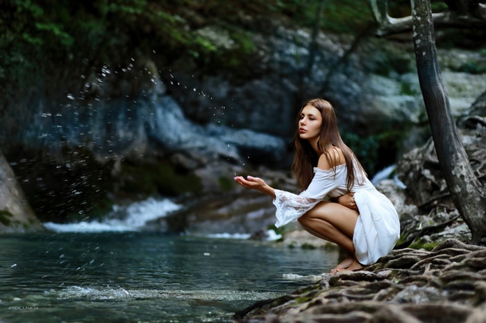 Girl in white dress by waterfall