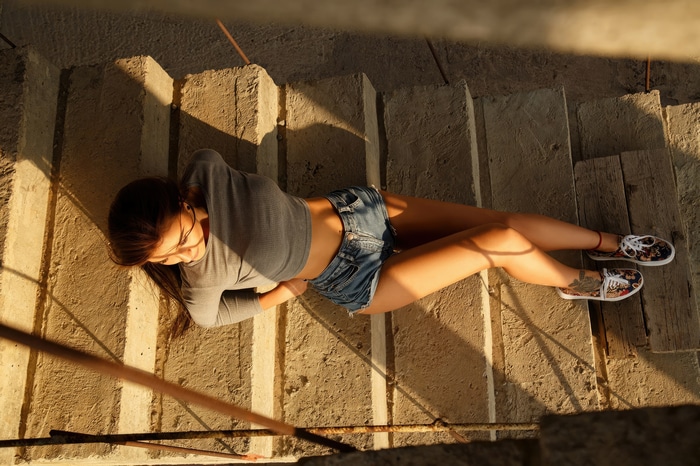 Model in denim shorts and grey top on stairs