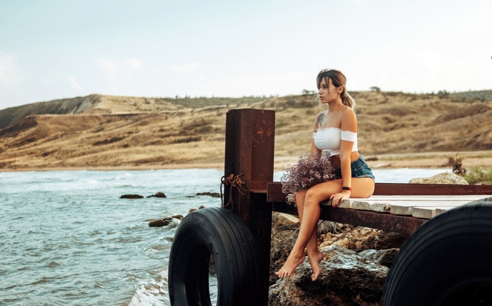 Girl sitting on a pier with flowers