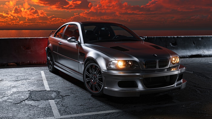 Silver BMW M3 parked by the ocean at sunset