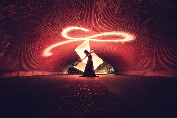 Woman with light painting in brick tunnel