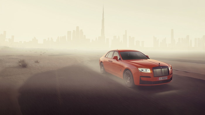 Orange Rolls Royce Ghost driving in Dubai desert