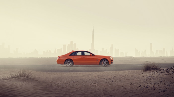 Orange Rolls-Royce Ghost in Desert with Dubai Skyline