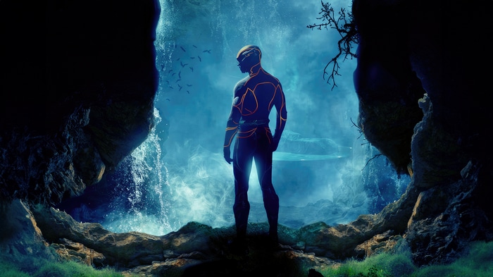 The Flash standing in a cave with a waterfall