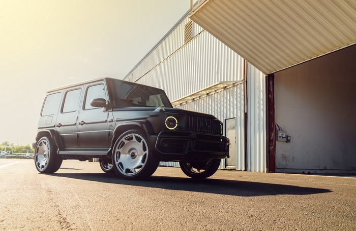 Black Mercedes G-Class SUV parked near a hangar
