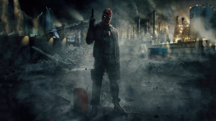 Red Hood stands in a destroyed industrial area