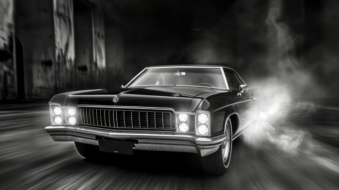Black classic car drifting with smoke
