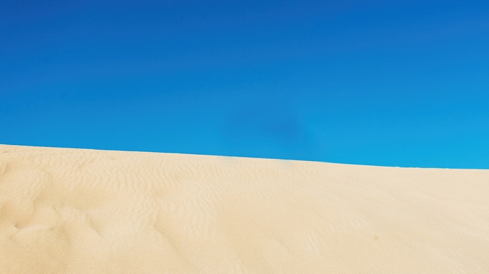 Desert sand dune under a clear blue sky