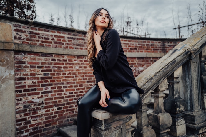 Model in black dress and leggings on stone stairs
