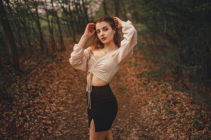 Model posing in a forest path
