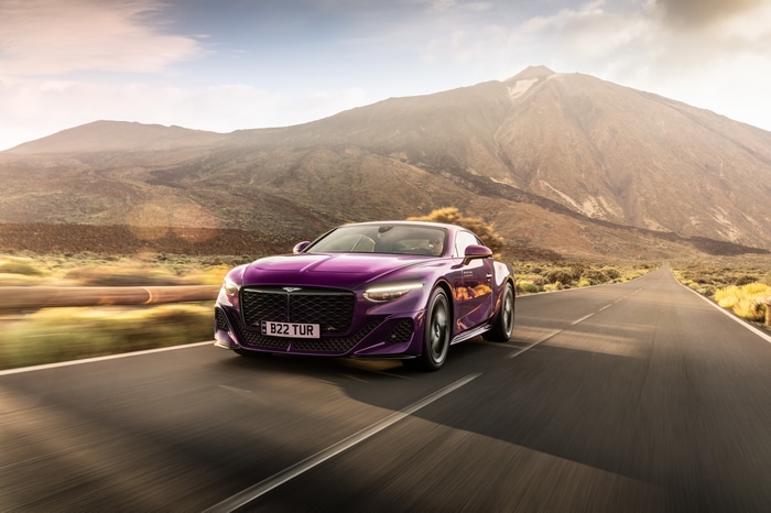 Purple Bentley Batur driving on a road with mountains