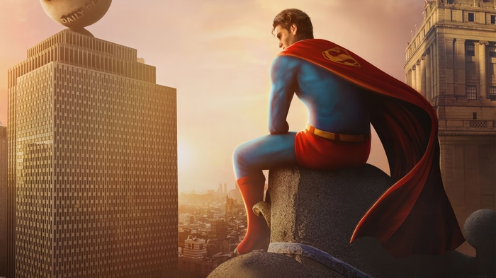 Superman sitting on a building overlooking a city at sunset