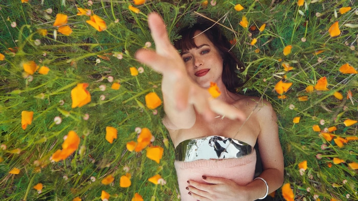 Dakota Johnson lying in a field of flowers