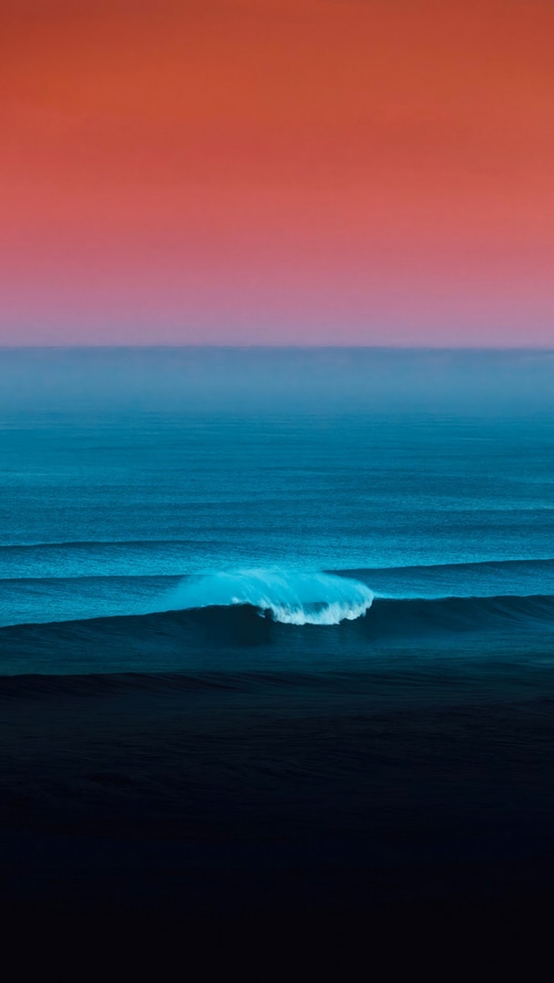 Ocean waves at sunset with orange and blue sky