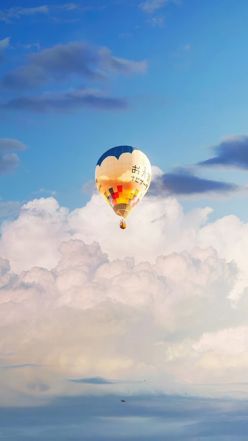 Hot air balloon floating in the sky above clouds